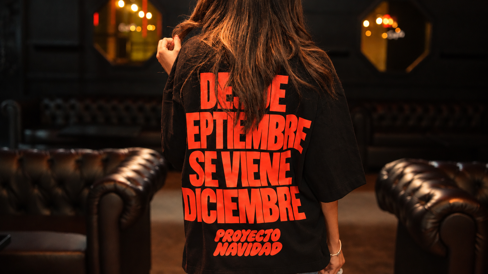 Persona de espaldas con camiseta negra de Proyecto Navidad y el mensaje Desde septiembre se viene diciembre